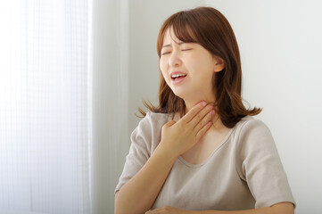 首のまわりが痛そうな若い女性