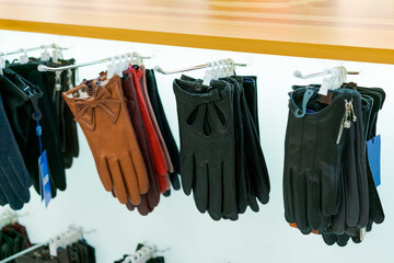 leather women's gloves hang on the counter in the store