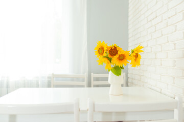 A bouquet of sunflowers in a vase are on the table