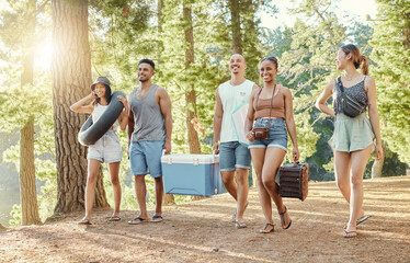 Group, friends and walking to picnic in the woods, forest or park in nature for summer, vacation...