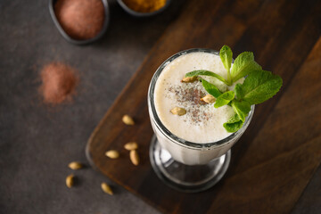 Indian Salty lassi with mint leaves and kala namak on black background. Traditional freshness lassi made of yogurt, water, spices and ice for hot climate. Close up. Copy space.