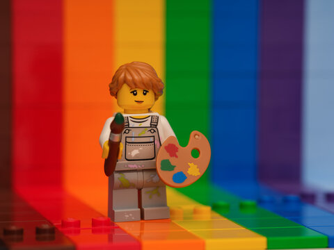 Tambov, Russian Federation - November 07, 2022 Lego girl painter minifigure with a paintbrush and a palette standing against a rainbow backdrop