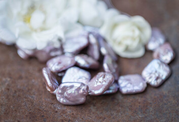 Natural freshwater pearls of various shapes and colors are photographed on a metall 