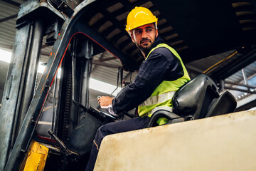 Man worker at forklift driver happy working in industry factory logistic ship. Man forklift driver in warehouse area. Forklift driver sitting in vehicle in warehouse. © kanpisut