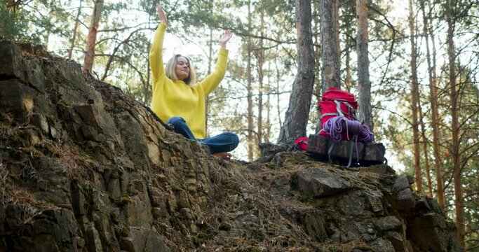 Breath of the forest and free your mind with meditation. 4k footage of a young woman start meditating in a morning pine forest. Solitude with your thoughts and nature. Nature as a path to mental