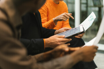 Fototapeta premium detail on hands multiracial people sitting working together on a project with sheets and tablet
