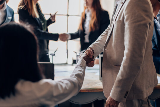 businessmen shaking hands in a meeting in an office with colleagues - renewable energy business