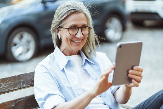 Integration of technology and daily lives of older individuals, and their ability to stay connected and engage in digital communication. Happy senior lady enjoying online conversation on tablet PC.