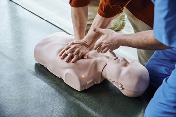 first aid training seminar, partial view of medical instructor pointing with hand and assisting man...