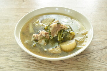 boiled mixed vegetable with pork bone in black soybean soup in plate on table 