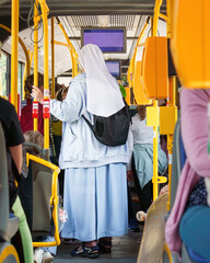 An authentic catholic elderly nun in a nun's dress inside a bus with multicultural passengers on a...