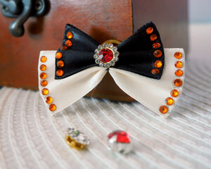 next to the wooden box is a small beige and black bow with a shiny red stone in the middle and...