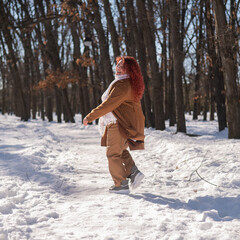 Portrait of an excited red-haired curly fat woman in the park in winter.