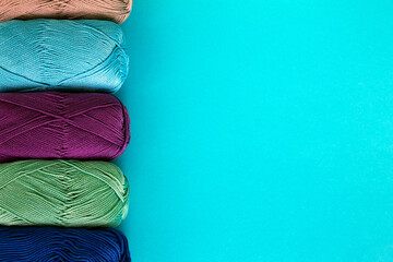 Colorful multi-colored background of skeins of cotton yarn arranged in a row on the right. Materials for knitting. Textile industry. 