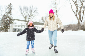 Fototapeta na wymiar little girl skater in a winter park having fun with her daughter