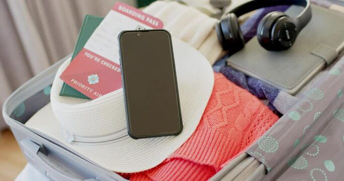 Close up of a plane ticket, passport, smartphone, tablet and headphones in suitcase