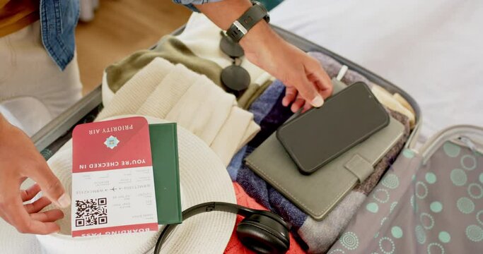 Close up of hands of biracial man packing suitcase in bright bedroom