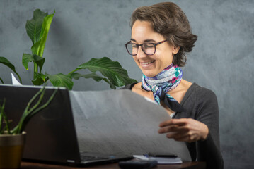 Mujer joven con lentes observa un papel en la oficina