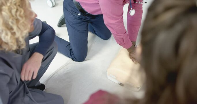 African american doctor training trainee doctors in emergency cpr procedure using dummy, slow motion