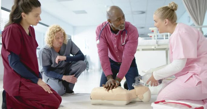 African american doctor training trainee doctors in emergency cpr procedure using dummy, slow motion