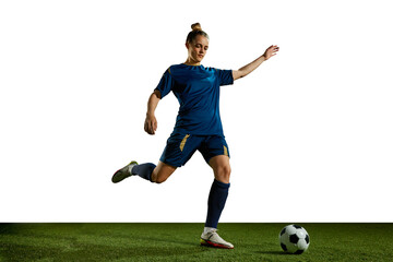 Obraz premium Young sportive girl in blue uniform, football player in motion, training, kicking ball against white background. Concept of professional sport, action, lifestyle, competition, hobby, training, ad