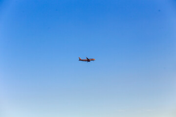 Airplane flying on blue sky background at sunsetAirplane flying on blue sky background at sunset