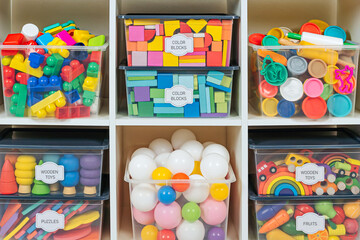 White shelving with colorful toys in plastic storage boxs. Interior design. Toys sorting system. ...