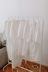 Fototapeta na wymiar white identical women's outfit on a hanger. Women's robes. A girl's evening in the same outfit