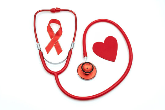 Top view photo of red stethoscope with red silk ribbon symbol of aids awareness and red heart on isolated white background with copyspace