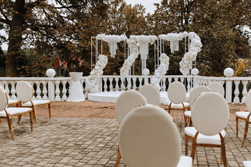 wedding ceremony in the park, prepared in white and gold colors, many chairs, luxurious preparation, no people