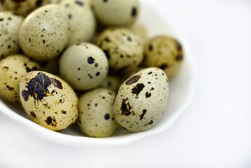 Obraz premium Quail eggs in a white plate. Food eggs on a white background.