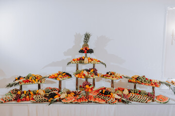 table with various fruit decorations. Watermelon carving, pineapple slices, grapes, orange