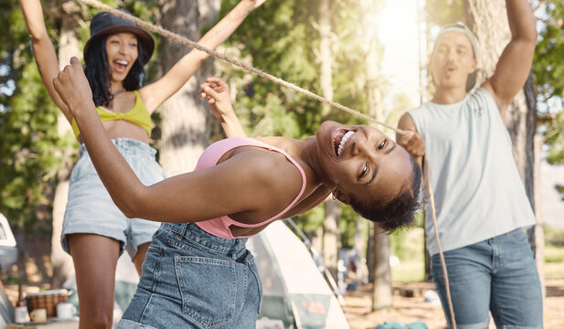 Happy, portrait and friends playing limbo for freedom, holiday games and camping activity. Smile, summer and a black woman having fun with a rope and social people while on vacation in a forest