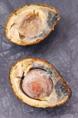 Old moldy avocado on dark board. Unhealthy and disgusting fruit