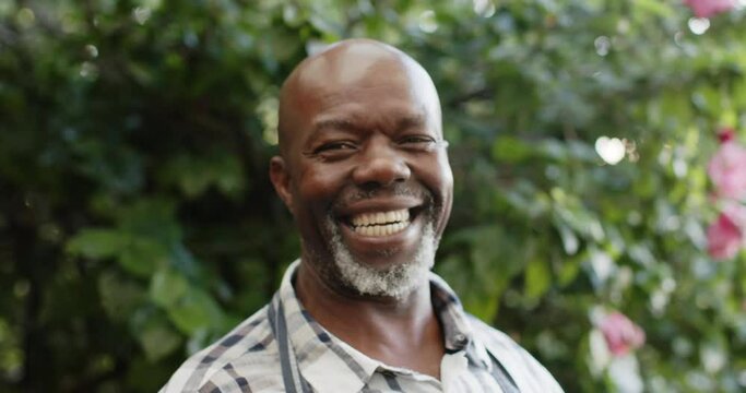 Portrait of happy senior african american male shopkeeper in nature, slow motion