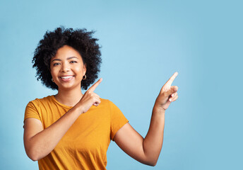 Happy, portrait of woman pointing and against blue background for giveaway. Direction or marketing, advertising or product placement and female person pose with hand gesture in studio backdrop