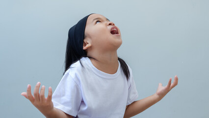 Little Asian girl kid wearing casual white tshirt crazy and mad shouting and yelling with...
