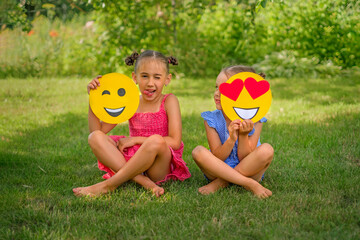 The girl makes faces, repeating the emoji. The child looks at his sister , closing eye with a yellow emoticon with hearts