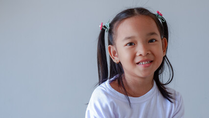 Little Asian girl smiling to the camera. The girl wearing casual white with pigtails