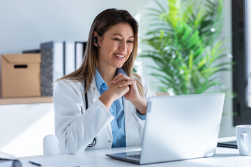 Female doctor talking with colleagues through a video call with a laptop in the consultation.