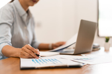 Close up hands of businesswoman working and reading financial document to writing notes in notebook