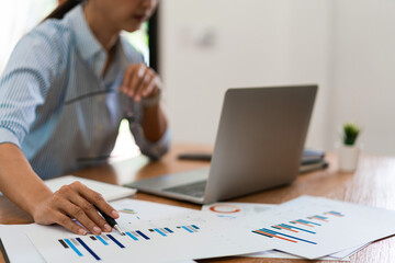 Close up hands of businesswoman reading financial business document and working on laptop in office