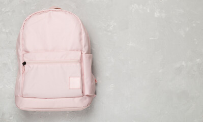 Pink school backpack on concrete background, top view