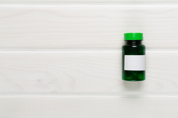 Plastic bottle with vitamins on wooden background, top view