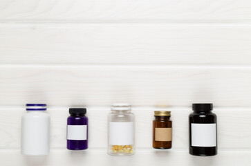 Plastic bottles with vitamins on wooden background, top view