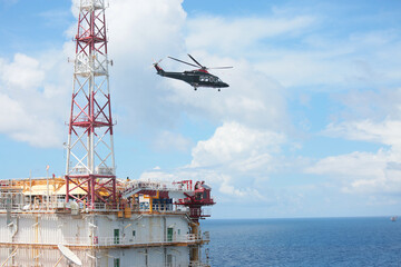 Helicopter Landing Officer communicating with pilot and copilot for service on ground and support as the pilot required. The helicopter landing on the deck in oil and gas platform