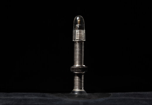 The nipple of a bicycle camera on a black, macro