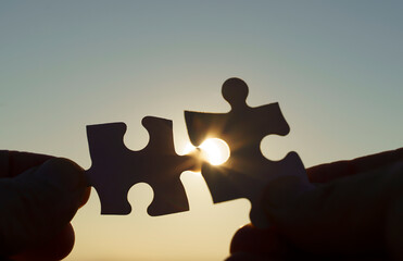  Puzzle pieces are connected. Puzzle pieces in hand on a sunny sky background. Business, partner,...