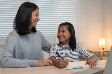 Mother teaching lesson for daughter. Asian young little girl learn at home. Do homework with kind mother help, encourage for exam.. Girl happy Homeschool. Mom advice education together.