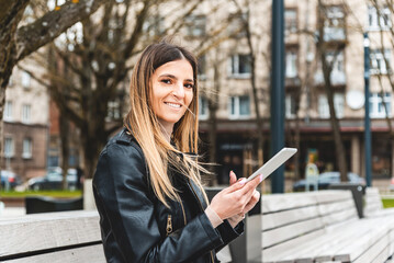 Fototapeta premium Young hipster girl holding pc tablet in the city.Traveler woman using tablet.reading guide book map on tablet computer pc,using mobile internet.Female writes text message or content.